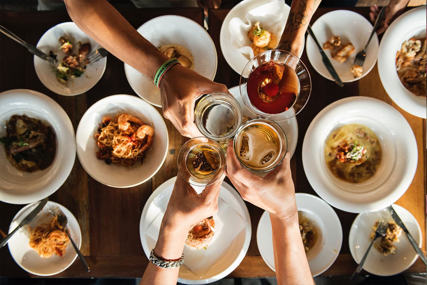 friends cheering their glasses of wine over plates of food
