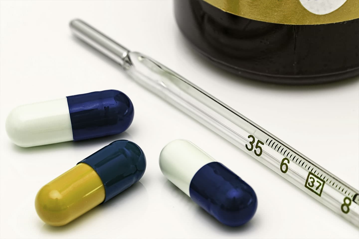 a few pills next to a thermometer