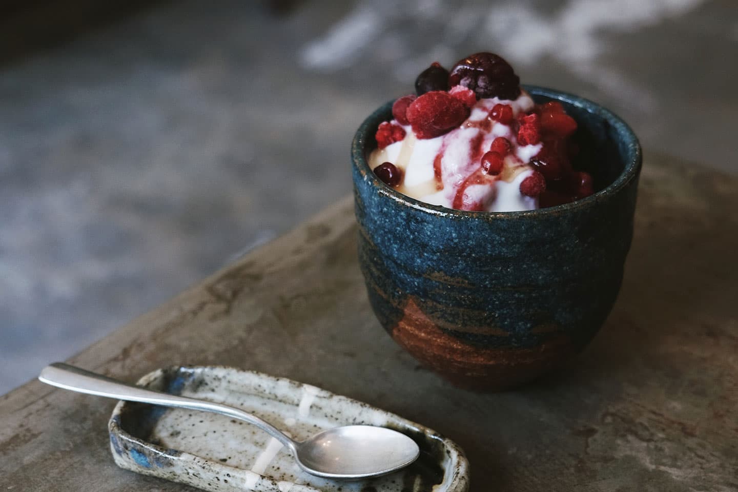 a spoon next to a mug of yogurt