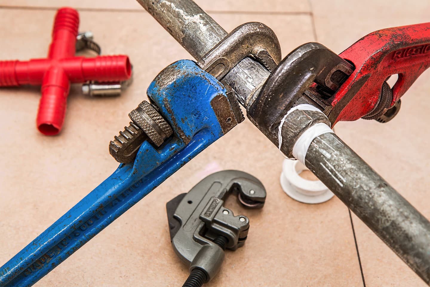 a leaky pipe being fixed with several wrenches
