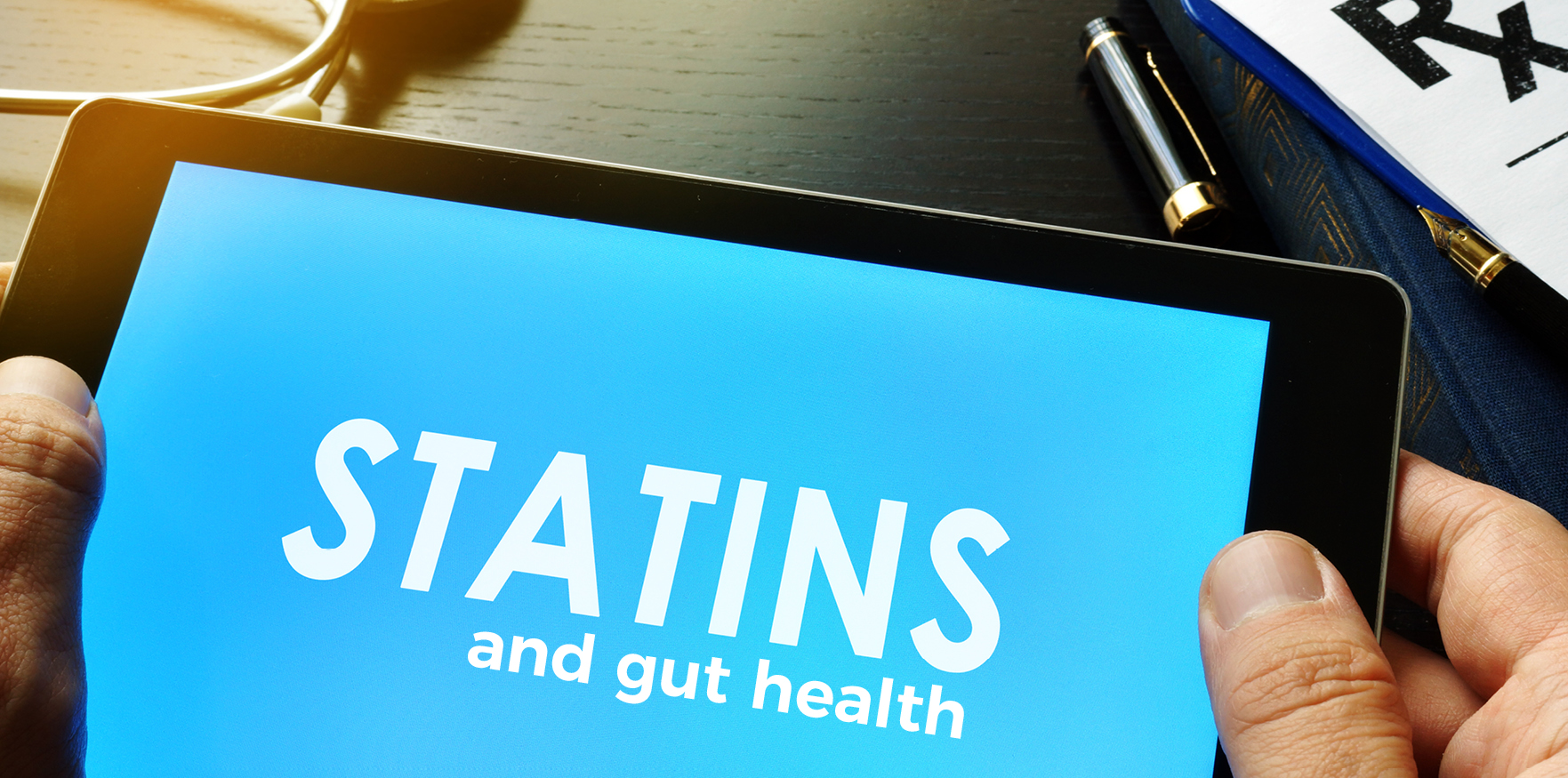 person holding tablet that displays text: "Statins and gut health"