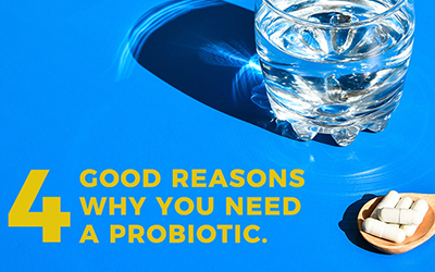 Glass of water next to five capsules. Text: 4 Good Reasons Why You Need A Probiotic