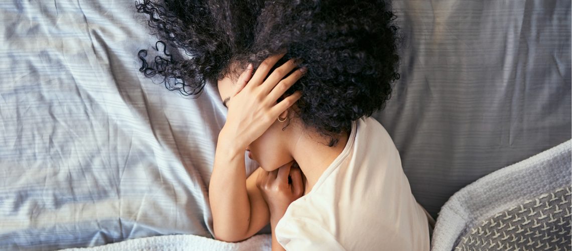 woman with migraine laying in bed